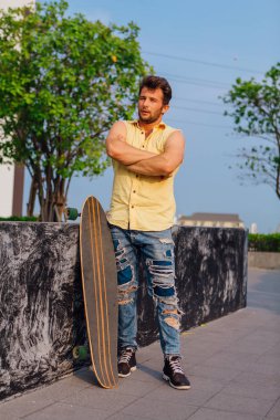 Genç yakışıklı adamla sokakta longboard ile sakal ayakta.