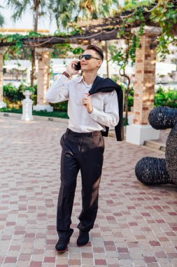 Genç işadamı telefonunu açık havada tropikal bir ülkede konuşurken