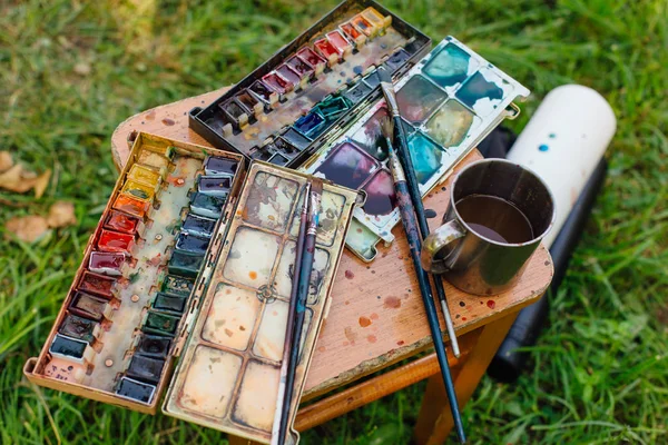 Paleta de tintas aquarela e pincéis no fundo de madeira . — Fotografia de Stock