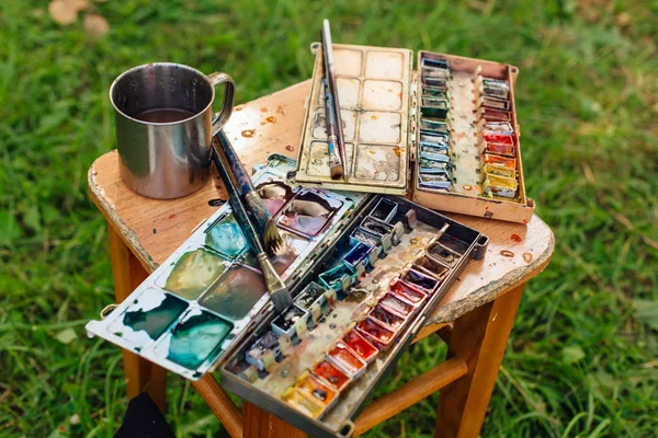 Palette of watercolor paints and brushes on the wooden background. — Stock Photo, Image