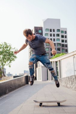 Kaykaycı kaykay numarası yapıyor. Bir şehrin caddesinde.