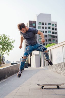 Kaykaycı kaykay numarası yapıyor. Bir şehrin caddesinde.
