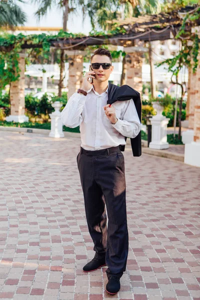 Genç işadamı telefonunu açık havada tropikal bir ülkede konuşurken