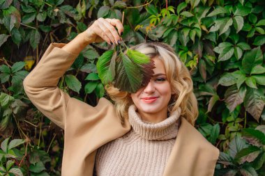 Sonbahar park yüzüne yakın yabani üzüm holding arka plan yanındaki güzel kadın kazak ve ceket durumda Yuong bırakır