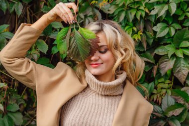 Sonbahar park yüzüne yakın yabani üzüm holding arka plan yanındaki güzel kadın kazak ve ceket durumda Yuong bırakır