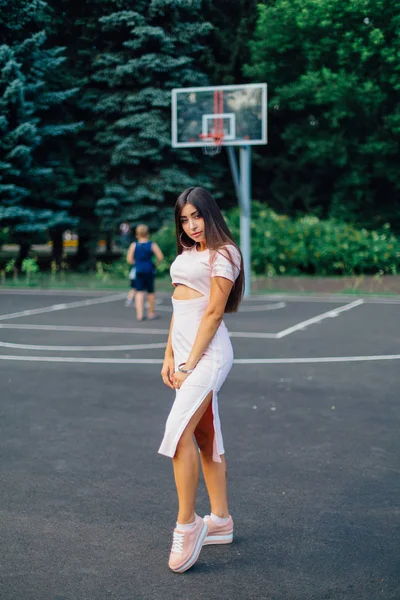 Encantadora Morena Vestida Con Vestido Rosa Posando Cancha Baloncesto Atardecer —  Fotos de Stock