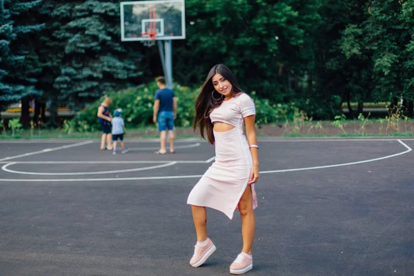 Charming Brunette Perempuan Mengenakan Gaun Merah Muda Berpose Lapangan Basket — Stok Foto