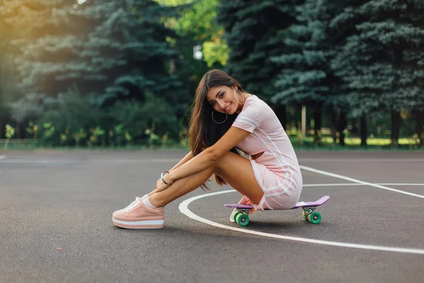 Portret Uśmiechniętej Uroczej Brunetki Siedzącej Deskorolce Boisku Koszykówki Szczęśliwa Kobieta — Zdjęcie stockowe