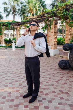 Genç işadamı telefonunu açık havada tropikal bir ülkede konuşurken