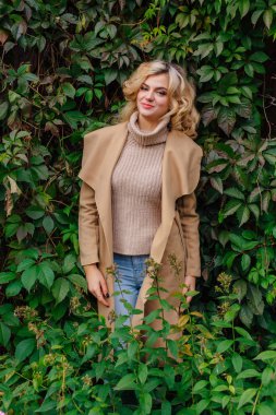 Yabani üzüm yaprakları Sonbahar Park arka plan yanındaki genç güzel kadın kazak ve ceket durumda