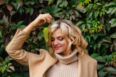 Yabani üzüm sonbahar park yüzüne yakın tutarak bırakır arka yanındaki genç güzel kadın kazak ve ceket durumda