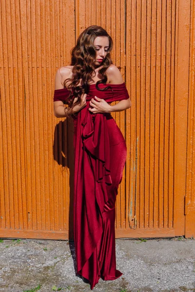 Eski kapı yanındaki bir tren konumu olan bir uzun kırmızı gece elbisesi güzel genç kadın