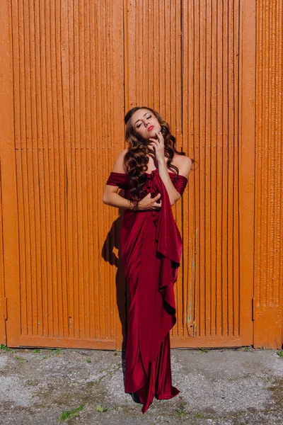 Eski kapı yanındaki bir tren konumu olan bir uzun kırmızı gece elbisesi güzel genç kadın