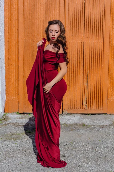 Eski kapı yanındaki bir tren konumu olan bir uzun kırmızı gece elbisesi güzel genç kadın