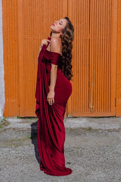 Eski kapı yanındaki bir tren konumu olan bir uzun kırmızı gece elbisesi güzel genç kadın