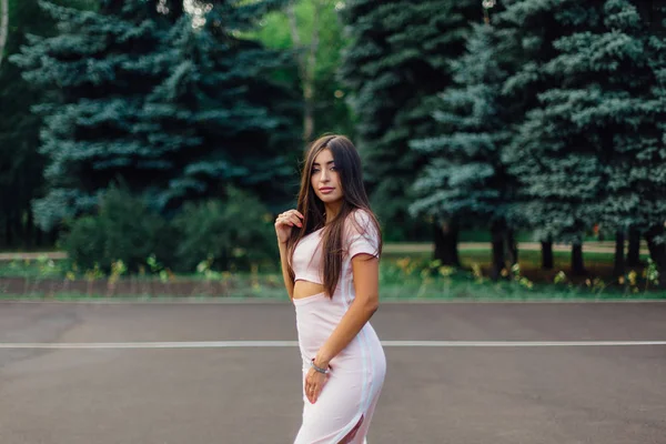 Şirin esmer erkek basketbol sahasına günbatımı sırasında poz pembe elbise giymiş.