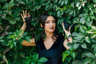 Siyah üzüm ile siyah elbiseli genç seksi esmer portresi. .