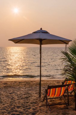Plaj sandalyeleri tropik adada günbatımı zaman şemsiye ile