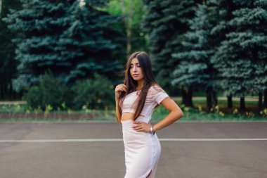 Şirin esmer erkek basketbol sahasına günbatımı sırasında poz pembe elbise giymiş.