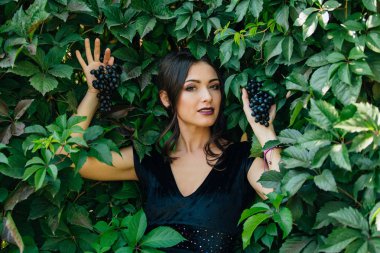 Siyah üzüm ile siyah elbiseli genç seksi esmer portresi. .