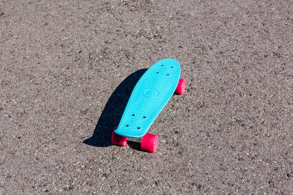 ピンクの車輪のついた青いプラスチック スケート ボード ペニー板トラックの上に立つ — ストック写真