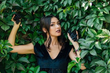 Siyah üzüm ile siyah elbiseli genç seksi esmer portresi. .