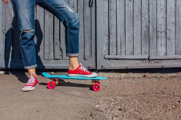 在红色运动鞋的女孩的脚关闭骑在蓝色塑料便士滑板与粉红色的车轮 都市风光 城市生活 健身生活方式 — 图库照片