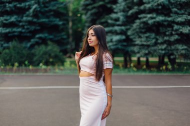 Şirin esmer erkek basketbol sahasına günbatımı sırasında poz pembe elbise giymiş.