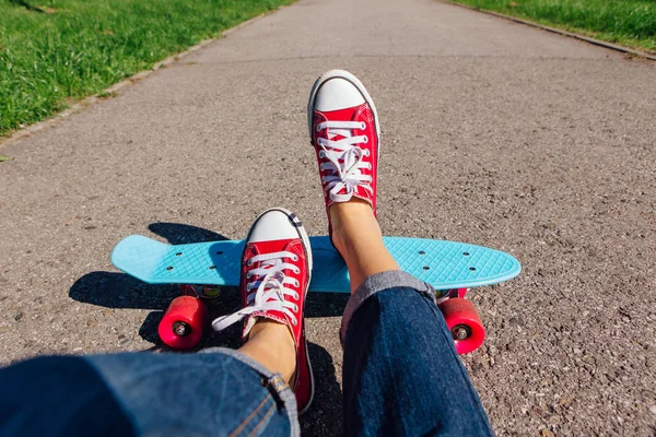 Close-up de pés na placa de skate de plástico azul penny com rodas rosa . — Fotografia de Stock