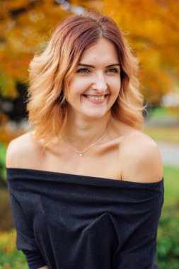 İle siyah elbiseli çekici bir kadın portresi açık omuz sonbahar rowan ağacı altında