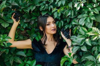 Siyah üzüm ile siyah elbiseli genç seksi esmer portresi. .