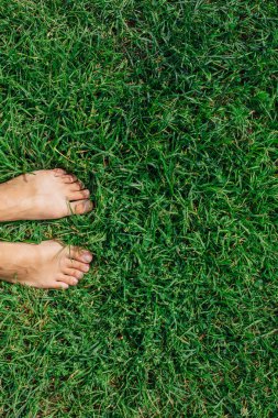 Çıplak kadının ayakları yeşil çimenlerin üzerinde