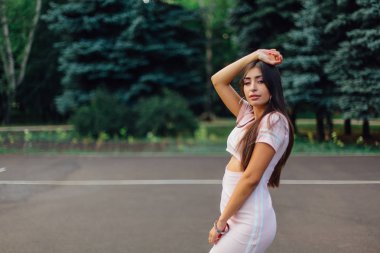 Şirin esmer erkek basketbol sahasına günbatımı sırasında poz pembe elbise giymiş.