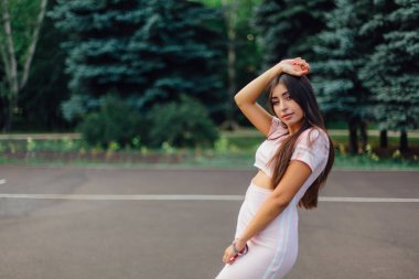 Şirin esmer erkek basketbol sahasına günbatımı sırasında poz pembe elbise giymiş.