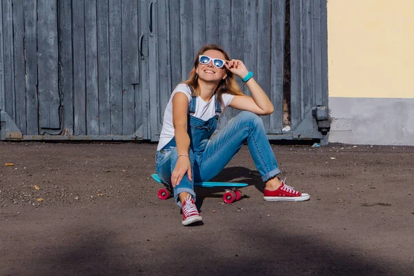 Porträtt Leende Kvinna Klädd Byxor Och Solglasögon Sitter Hennes Skateboard — Stockfoto