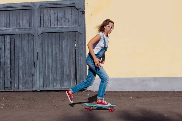Tulum ve eski ahşap duvar yanındaki plastik onun kaykay sürme güneş gözlüğü gülümseyen bir kadın portresi giymiş.