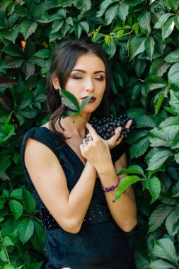 Siyah üzüm ile siyah elbiseli genç seksi esmer portresi. .
