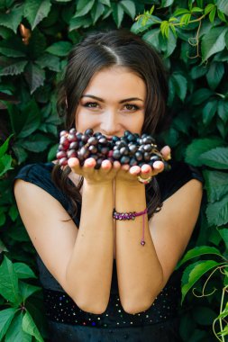 Siyah üzüm ile siyah elbiseli genç seksi esmer portresi. .