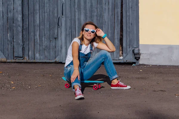 Porträtt Leende Kvinna Klädd Byxor Och Solglasögon Sitter Hennes Skateboard — Stockfoto