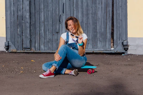 Portrait Smiling Woman Dressed Overalls Sunglasses Sitting Her Skateboard Next — Stock Photo, Image