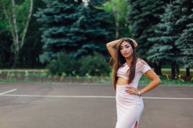 Şirin esmer erkek basketbol sahasına günbatımı sırasında poz pembe elbise giymiş.