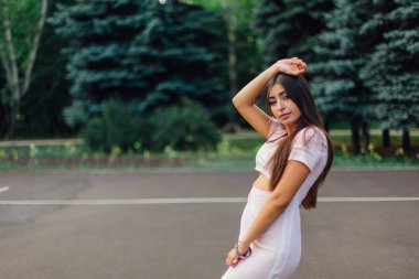 Şirin esmer erkek basketbol sahasına günbatımı sırasında poz pembe elbise giymiş.