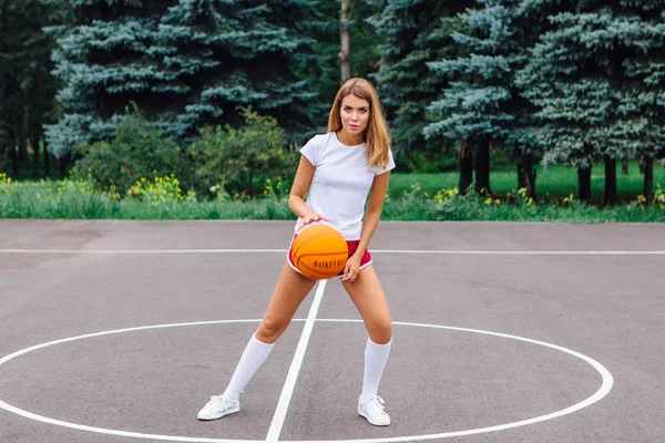 티셔츠에 반바지를 운동화를 아리따운 소녀가 농구장 밖에서 가지고 — 스톡 사진