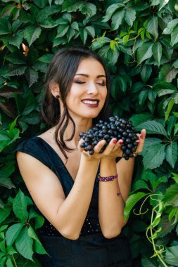Siyah üzüm ile siyah elbiseli genç seksi esmer portresi.