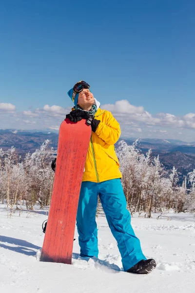Mutlu genç erkek snowboard snowboard kış tatil yaparken dağ ile