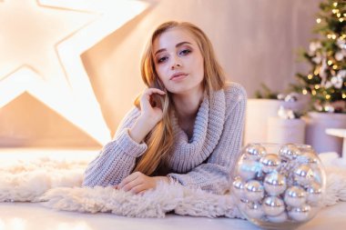 Güzel genç sarışın bir kadın büyük Star kase ile Noel ağacı tam bir tatil iç gümüş topları ile döşeme beyaz kazak giymiş.