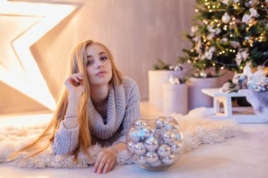 Güzel genç sarışın bir kadın büyük Star kase ile Noel ağacı tam bir tatil iç gümüş topları ile döşeme beyaz kazak giymiş.