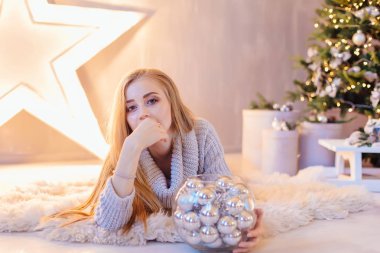 Güzel genç sarışın bir kadın büyük Star kase ile Noel ağacı tam bir tatil iç gümüş topları ile döşeme beyaz kazak giymiş.