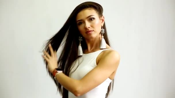 Vacker ung kvinna poserar på den vita bakgrunden — Stockvideo