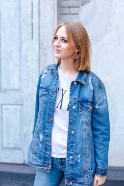 Büyük boy kot ceket ve güzel kulak yüzük tuğla duvara yakın duran kız moda.